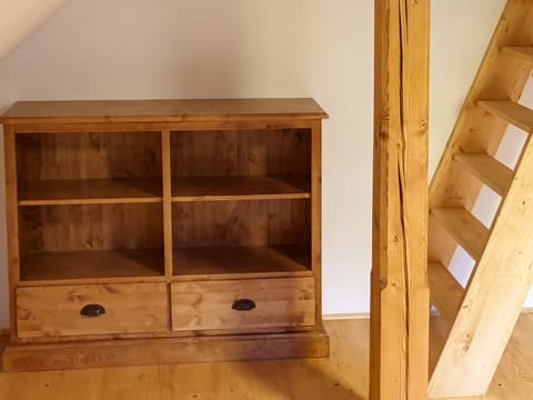 Nízký otevřený regál a knihovna z masivního dřeva vyrobená na míru do suterénního prostoru pod schodištěm.