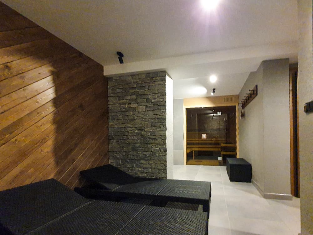 Relaxační místnost se saunou, kamenným obkladem a černými lehátky pro dokonalý odpočinek.