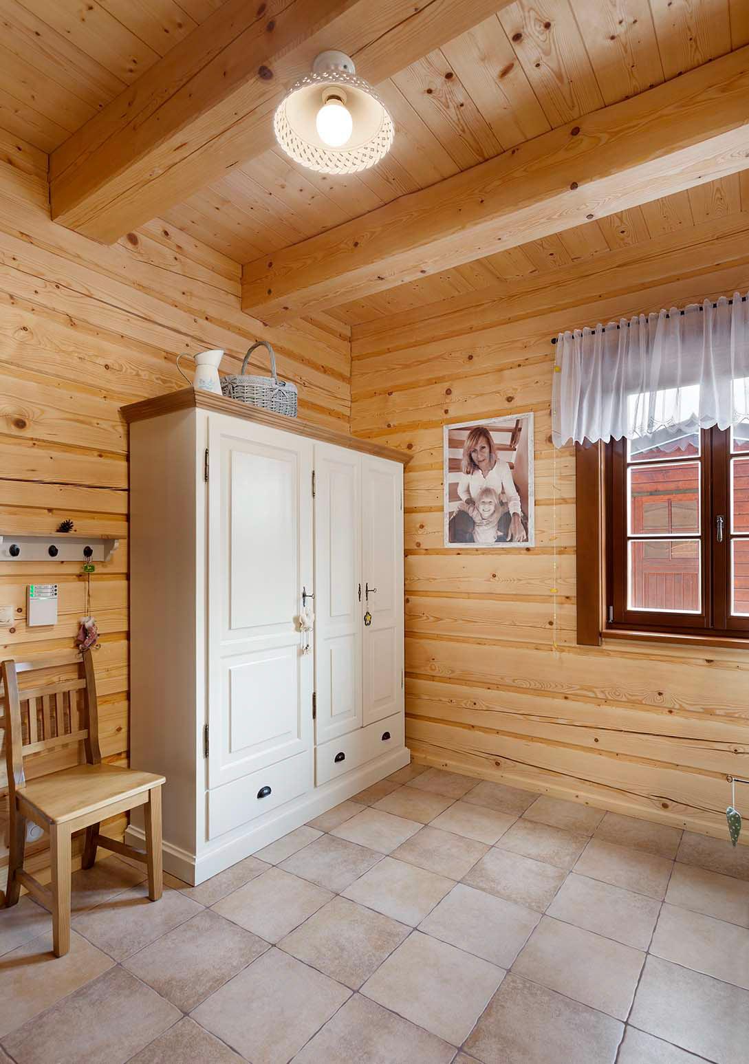 Volně stojící dvoudveřová šatní skříň z masivního dřeva v selském stylu v podkrovním pokoji.