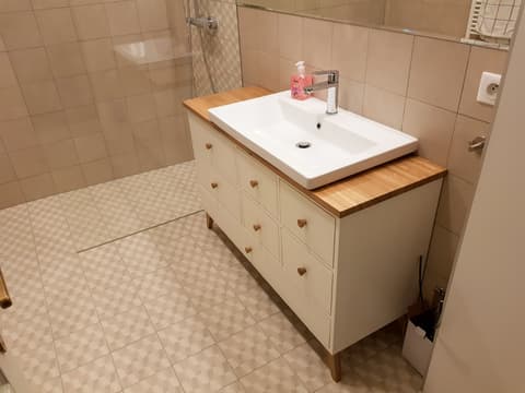 Bílá koupelnová skříňka z masivu s dřevěnou horní deskou a velkým bílým umyvadlem.