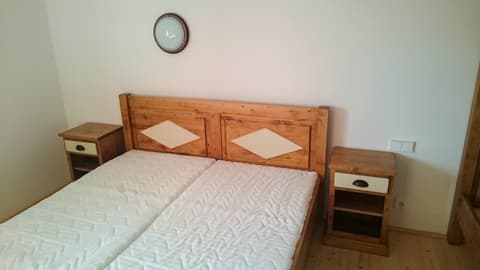 Elegantní manželská postel z přírodního masivu se světlými ozdobnými kosočtverci frézovanými v hlavovém čele.