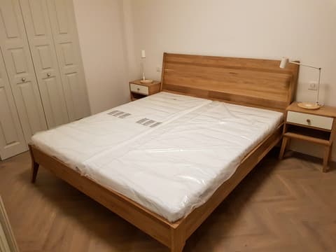 Manželská postel z masivního dřeva v přírodním odstínu v jednoduchém moderním designu pro venkovský dům.