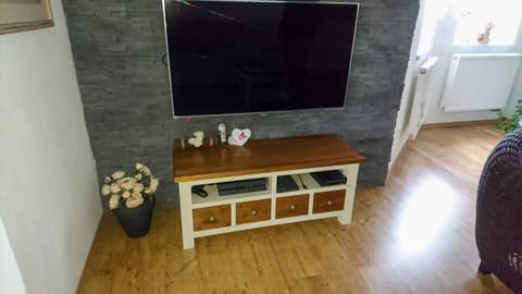 Dřevěný TV stolek a komoda z masivu s úložnými košíky v obývacím pokoji.