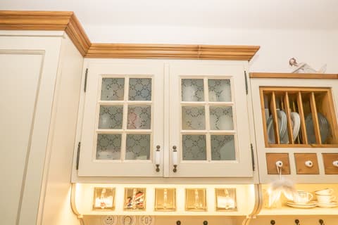 Dvoudveřová horní skříňka do kuchyně s děleným sklem, římsou a integrovaným spodním LED osvětlením.