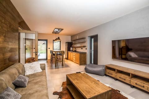 Propojený prostor s moderní kuchyňskou linkou z masivu a posezením v interiéru horského apartmánu Chalet Lucie.