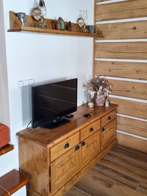 Dlouhá dřevěná TV komoda z poctivého masivu umístěná v roubence.