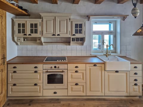 Rovná kuchyňská linka z masivního dřeva s elegantním frézováním a čirými okenními tabulkami ve dvířkách.
